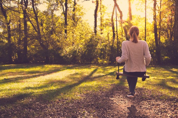 Girl Sitting Alone On Swing In Autumn
